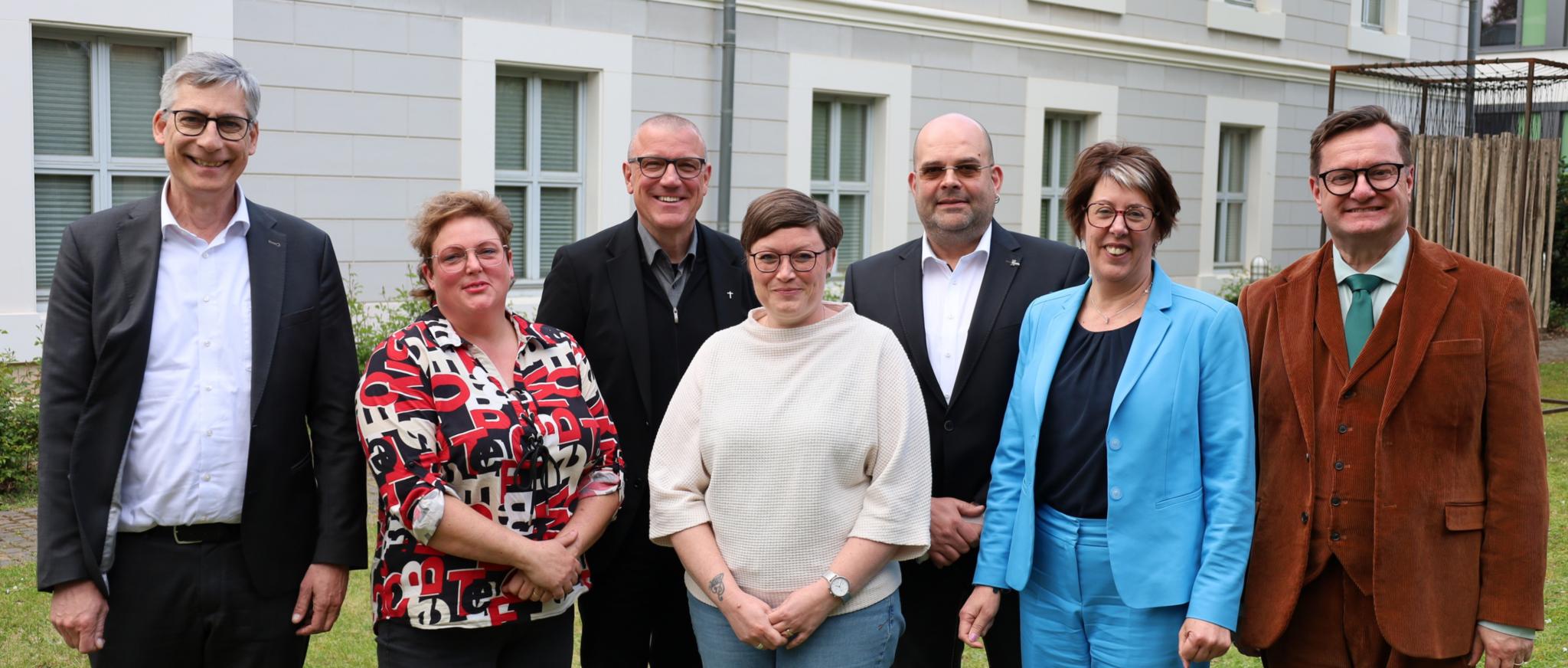 Sieben Personen vor einem Gebäude stehend